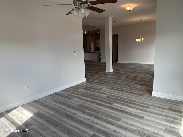 unfurnished living room featuring hardwood / wood-style floors and ceiling fan with notable chandelier