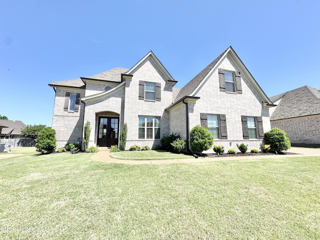 french country inspired facade featuring french doors, brick siding, and a front yard