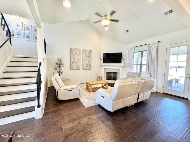 living area featuring ceiling fan, stairway, visible vents, and dark wood-type flooring