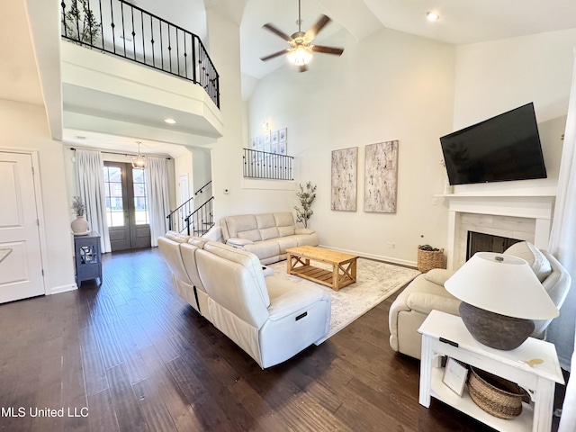 living area featuring stairway, dark wood finished floors, a fireplace, and ceiling fan