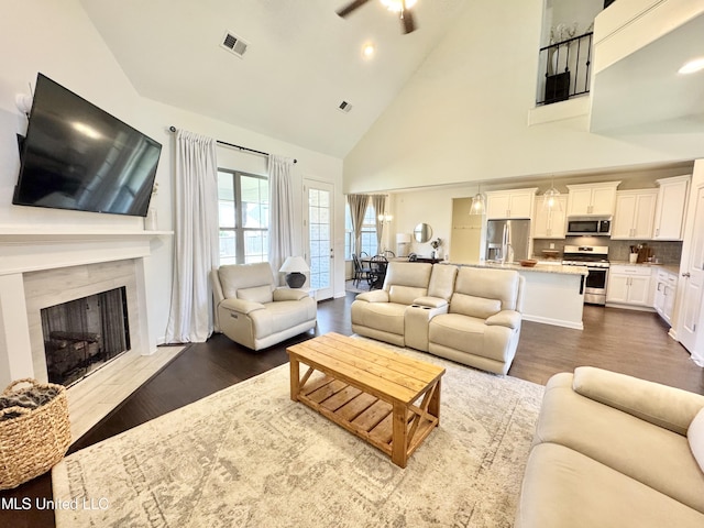 living room with high vaulted ceiling, visible vents, a fireplace, dark wood-style flooring, and a ceiling fan