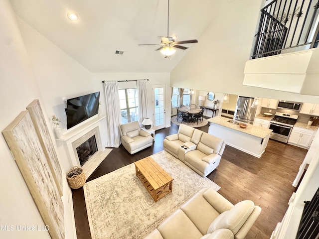 living room with ceiling fan, dark wood finished floors, high vaulted ceiling, and visible vents
