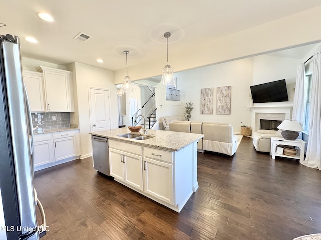 kitchen featuring visible vents, a sink, open floor plan, stainless steel appliances, and dark wood-style floors