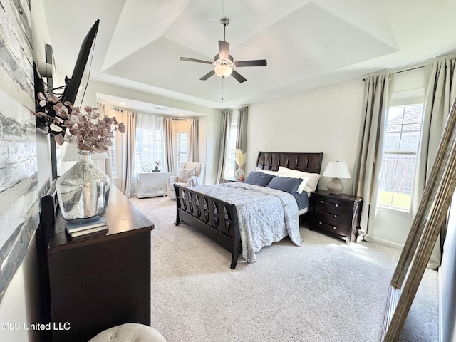 carpeted bedroom featuring a raised ceiling and ceiling fan