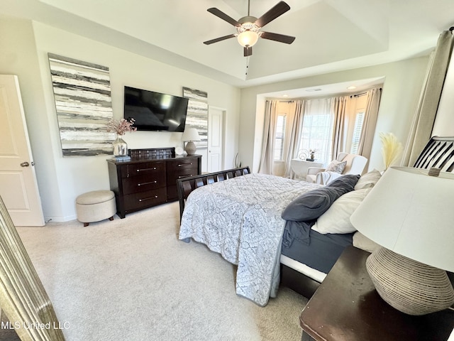 carpeted bedroom with a tray ceiling, baseboards, and ceiling fan