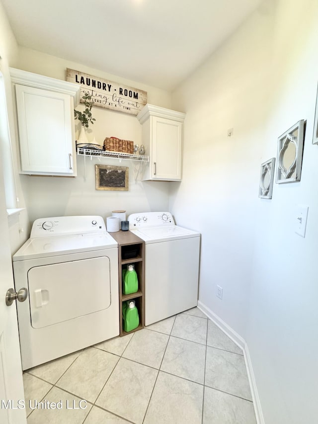 washroom featuring cabinet space, washer and clothes dryer, baseboards, and light tile patterned floors