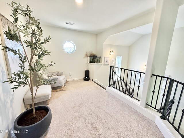 sitting room featuring an upstairs landing, carpet, visible vents, and a wealth of natural light