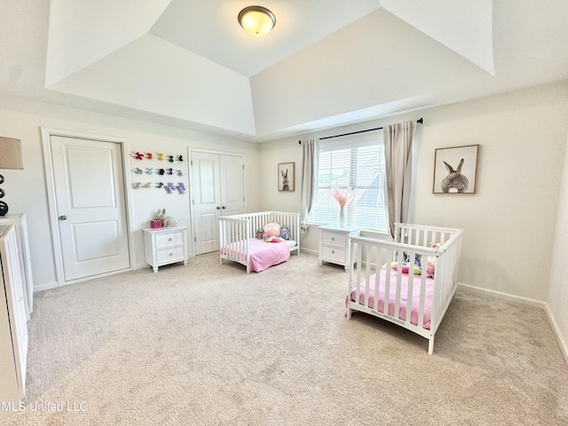 bedroom featuring a raised ceiling, carpet flooring, a nursery area, and baseboards