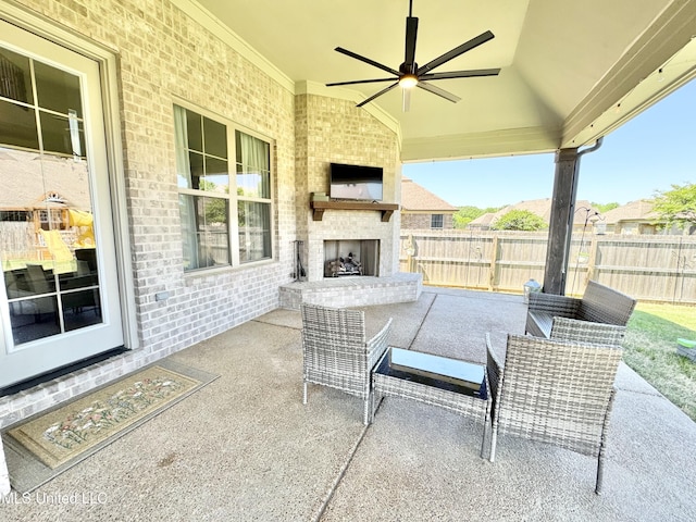 view of patio with fence, an outdoor brick fireplace, and ceiling fan