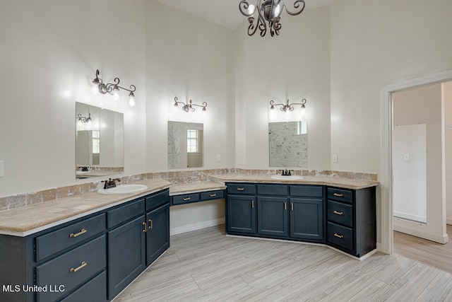 bathroom featuring a chandelier, vanity, hardwood / wood-style floors, and a towering ceiling