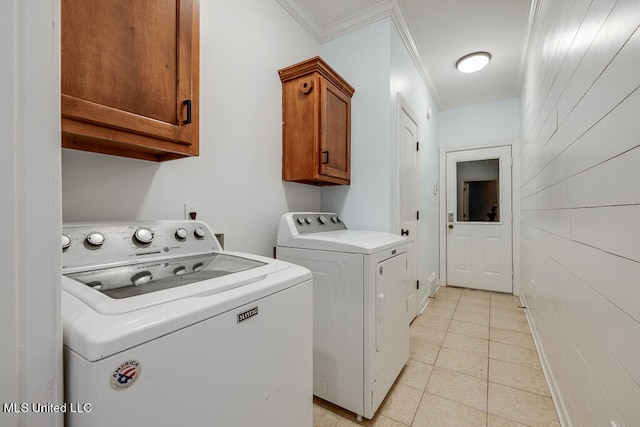 laundry area with light tile patterned floors, crown molding, washing machine and dryer, and cabinets