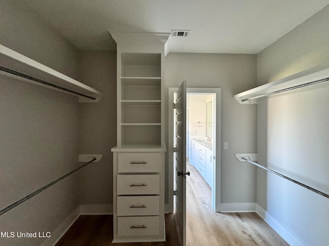 walk in closet featuring visible vents, a sink, and wood finished floors