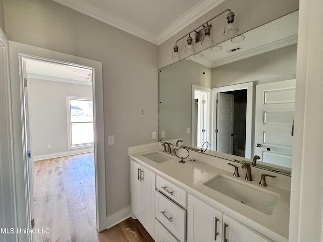 bathroom featuring wood finished floors, ornamental molding, a sink, and visible vents