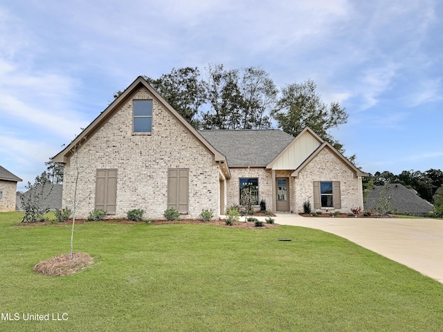 view of front of house featuring brick siding, roof with shingles, board and batten siding, and a front yard