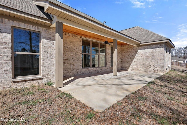 rear view of property featuring a ceiling fan, roof with shingles, and a patio