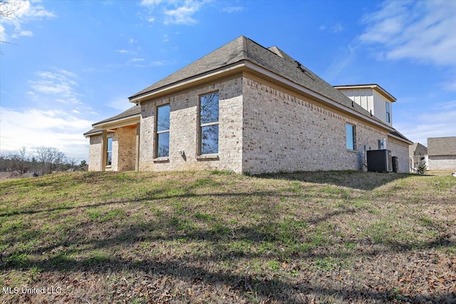 view of home's exterior with brick siding, a yard, and central air condition unit