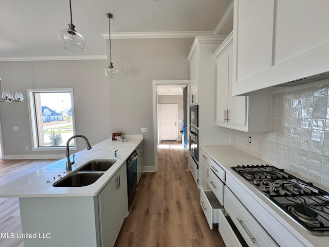 kitchen featuring crown molding, stainless steel appliances, decorative backsplash, white cabinets, and a sink