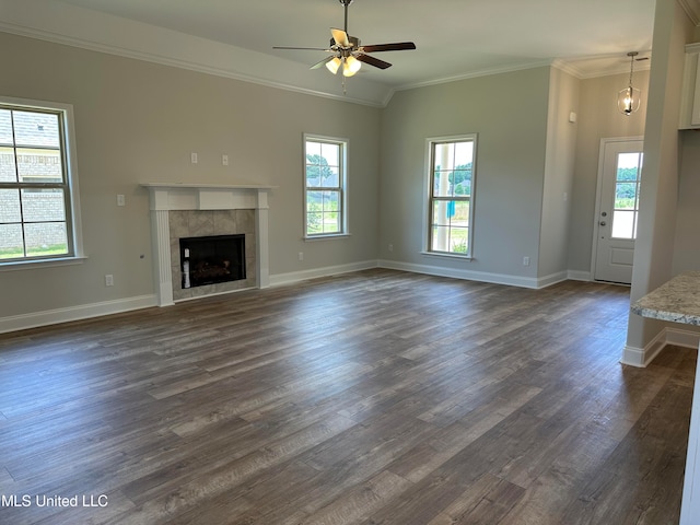 unfurnished living room with lofted ceiling, a tile fireplace, crown molding, ceiling fan, and dark hardwood / wood-style flooring