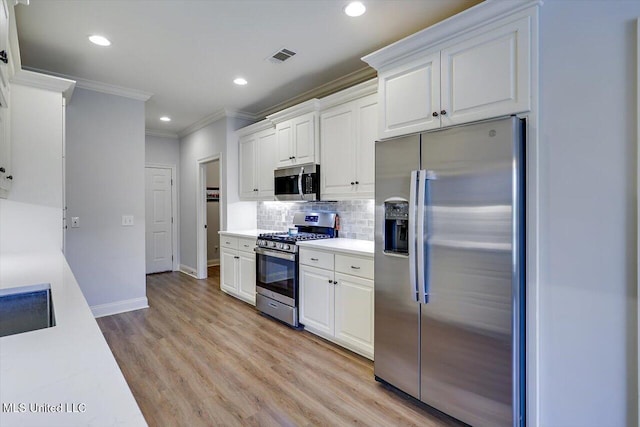 106 Sumter Dr, Canton, MS 39046 - kitchen featuring appliances with stainless steel finishes, crown molding, baseboards, white cabinets, and light countertops