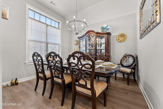 dining room featuring dark wood-type flooring, lofted ceiling, and an inviting chandelier