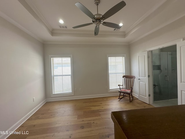 unfurnished room featuring ceiling fan, a raised ceiling, light hardwood / wood-style flooring, and crown molding