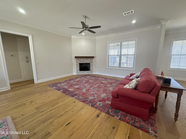 living room featuring ceiling fan, hardwood / wood-style flooring, ornamental molding, and plenty of natural light