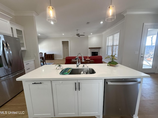 kitchen featuring white cabinets, a kitchen island with sink, stainless steel appliances, and pendant lighting