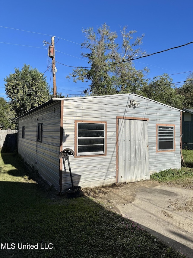 view of outdoor structure featuring fence and an outbuilding