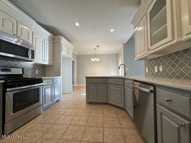 kitchen with light tile patterned floors, gray cabinets, appliances with stainless steel finishes, ornamental molding, and decorative light fixtures