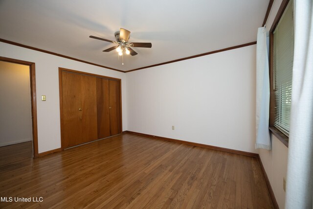 unfurnished bedroom featuring ornamental molding, a closet, dark hardwood / wood-style floors, and ceiling fan