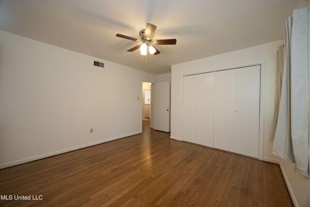 unfurnished bedroom with a closet, ceiling fan, and dark hardwood / wood-style flooring