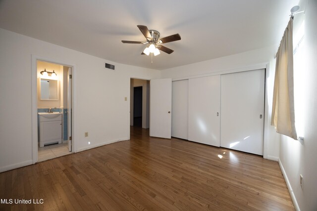 unfurnished bedroom with ceiling fan, light wood-type flooring, ensuite bathroom, a closet, and sink