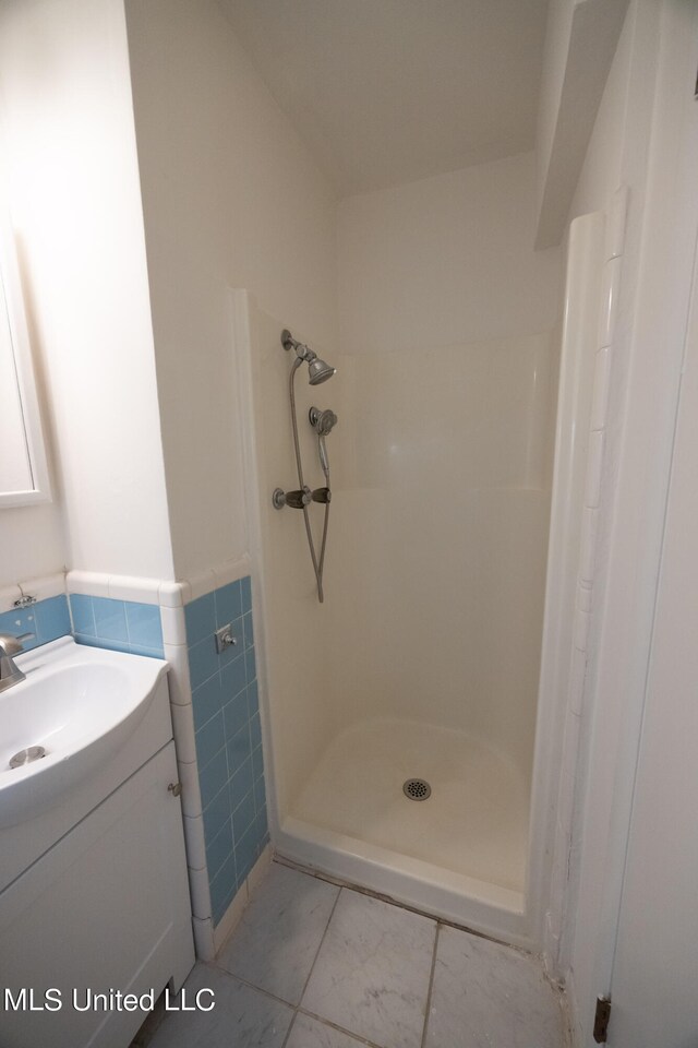 bathroom featuring vanity, a shower, and tile walls