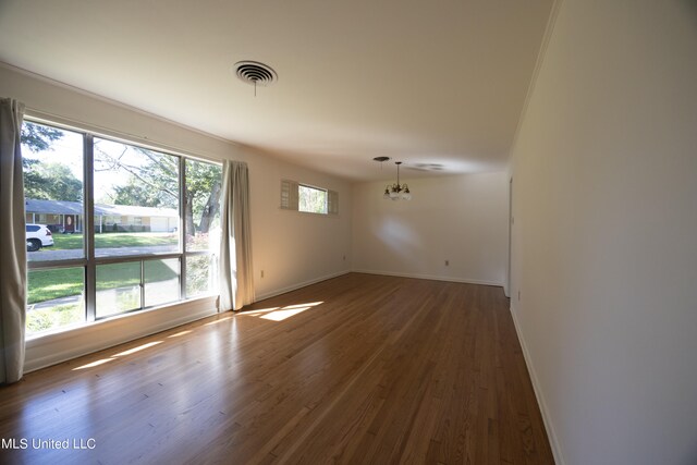 unfurnished room featuring hardwood / wood-style flooring and an inviting chandelier