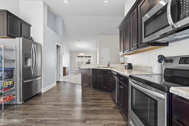 kitchen with a sink, dark wood-style floors, stainless steel appliances, a peninsula, and dark brown cabinets