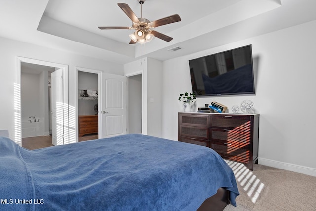 carpeted bedroom with a tray ceiling, visible vents, baseboards, and ceiling fan