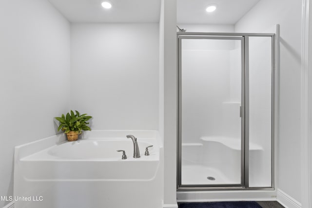 bathroom with a shower stall, a bath, and recessed lighting