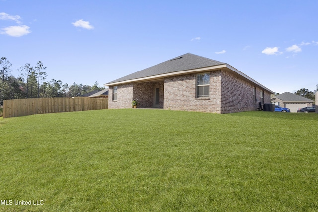 view of home's exterior featuring brick siding, a lawn, and fence