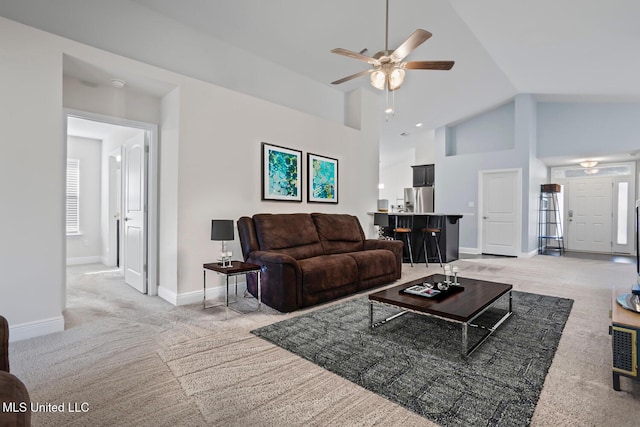 living area featuring baseboards, light carpet, high vaulted ceiling, and a ceiling fan