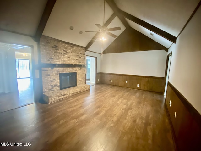 unfurnished living room featuring lofted ceiling with beams, hardwood / wood-style flooring, a brick fireplace, and ceiling fan