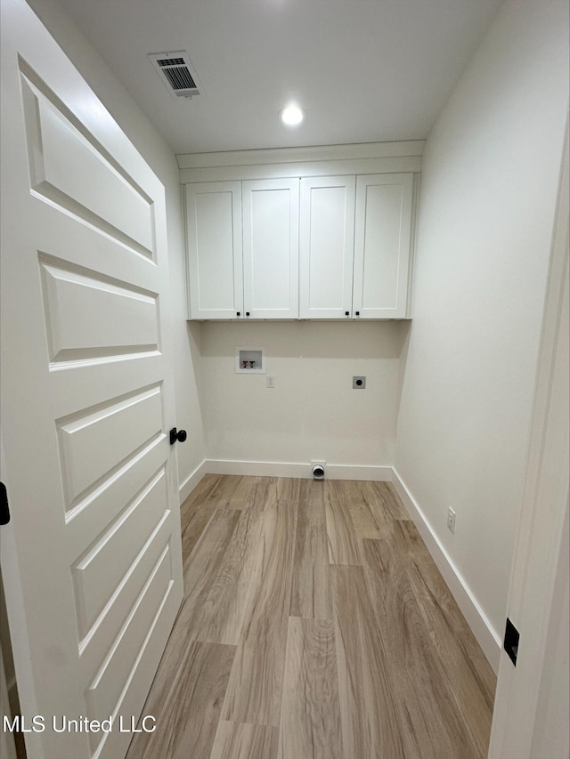 laundry area featuring electric dryer hookup, washer hookup, light hardwood / wood-style flooring, and cabinets