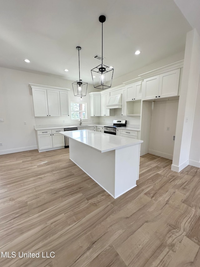 kitchen with white cabinetry, stainless steel appliances, a center island, custom range hood, and decorative light fixtures