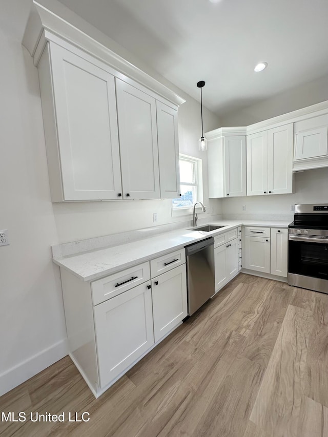 kitchen with white cabinetry, light hardwood / wood-style floors, decorative light fixtures, and appliances with stainless steel finishes