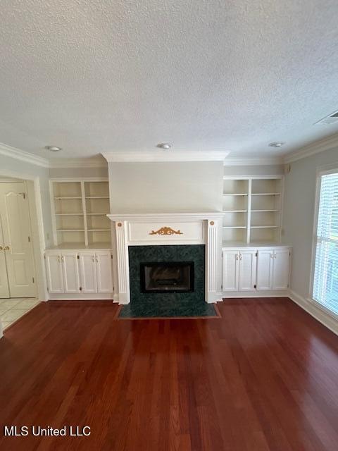 unfurnished living room featuring crown molding, dark hardwood / wood-style floors, a textured ceiling, and a fireplace