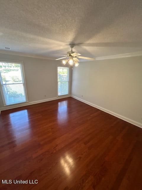 spare room with dark wood-type flooring, a textured ceiling, and a healthy amount of sunlight