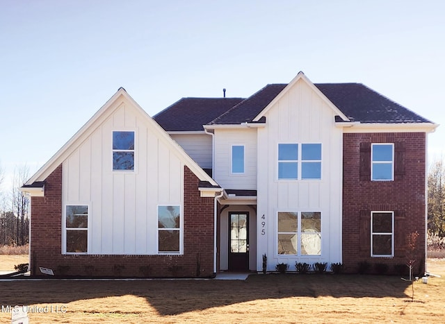 view of front of house with board and batten siding, brick siding, and a shingled roof