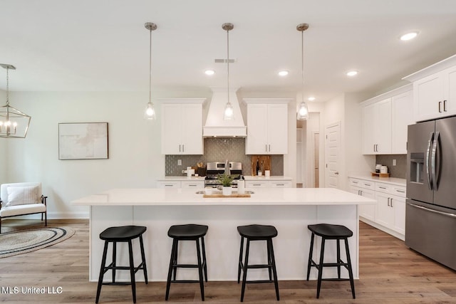 kitchen with white cabinetry, appliances with stainless steel finishes, a center island with sink, and pendant lighting