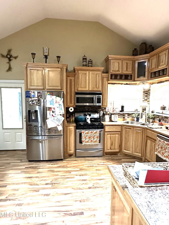 kitchen featuring light wood-type flooring, appliances with stainless steel finishes, lofted ceiling, and sink