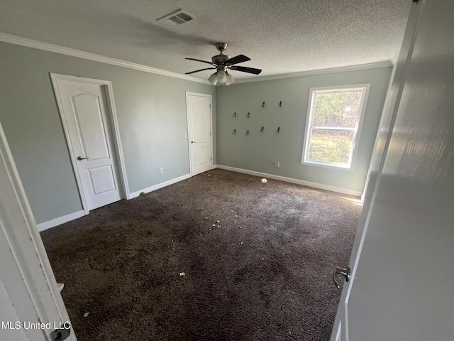 unfurnished bedroom featuring baseboards, a textured ceiling, crown molding, and carpet