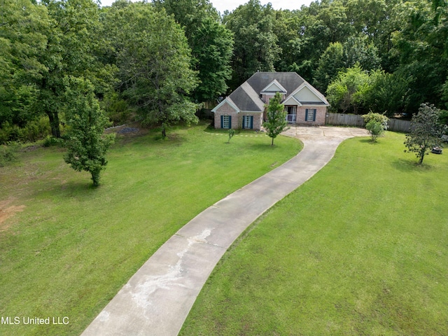 view of front of property with concrete driveway, a wooded view, and brick siding